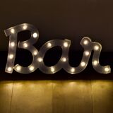 Enseigne lumineuse en lettrage aluminium formant le mot "bar"