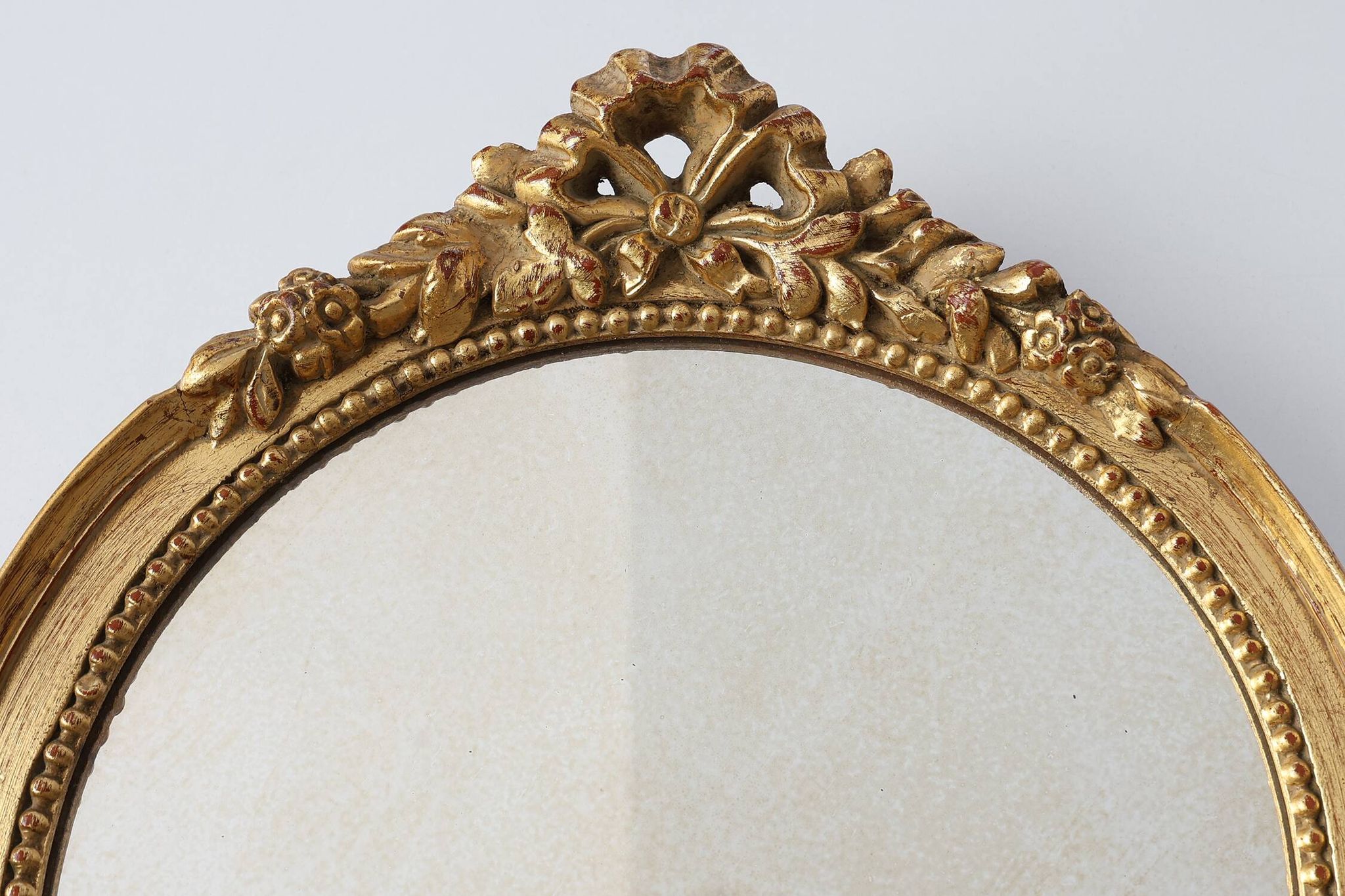 Oval giltwood mirror with rococo-style floral crest, mid-20th century