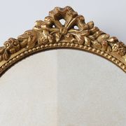 Oval giltwood mirror with rococo-style floral crest, mid-20th century