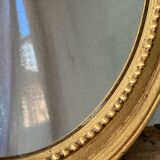 Oval-shaped wooden mirror in gold color