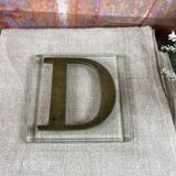 Metal letter D on glass plate