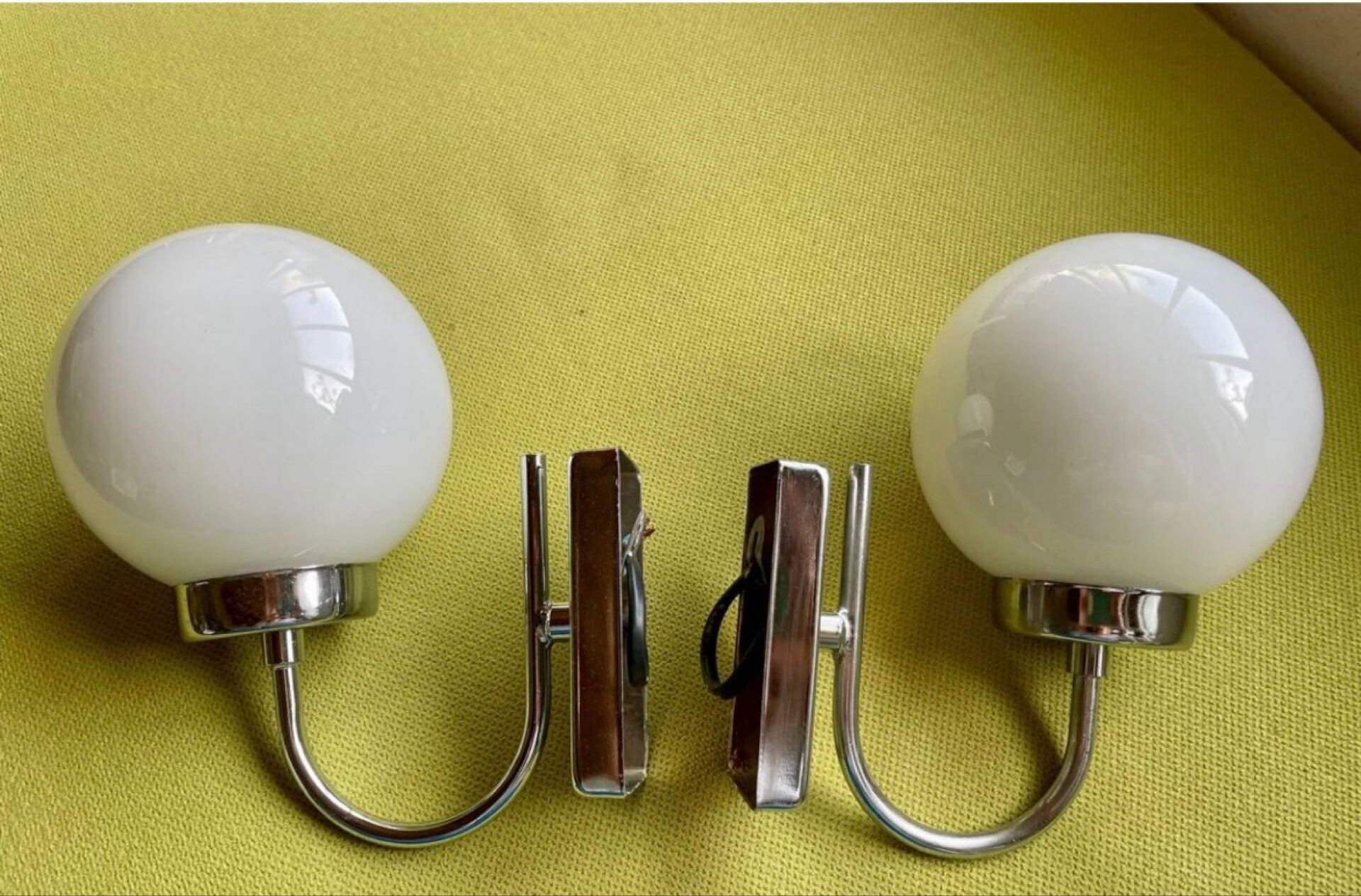 Pair of chrome metal wall lights with white glass globe.