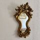 Antique rococo mirror with putti, gilded carved wood and stucco frame, 19th century.