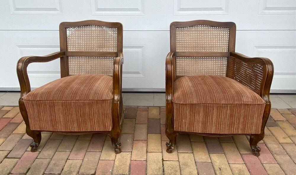 Pair of 1920s brown armchairs in carved wood and fabric, with caning detail.