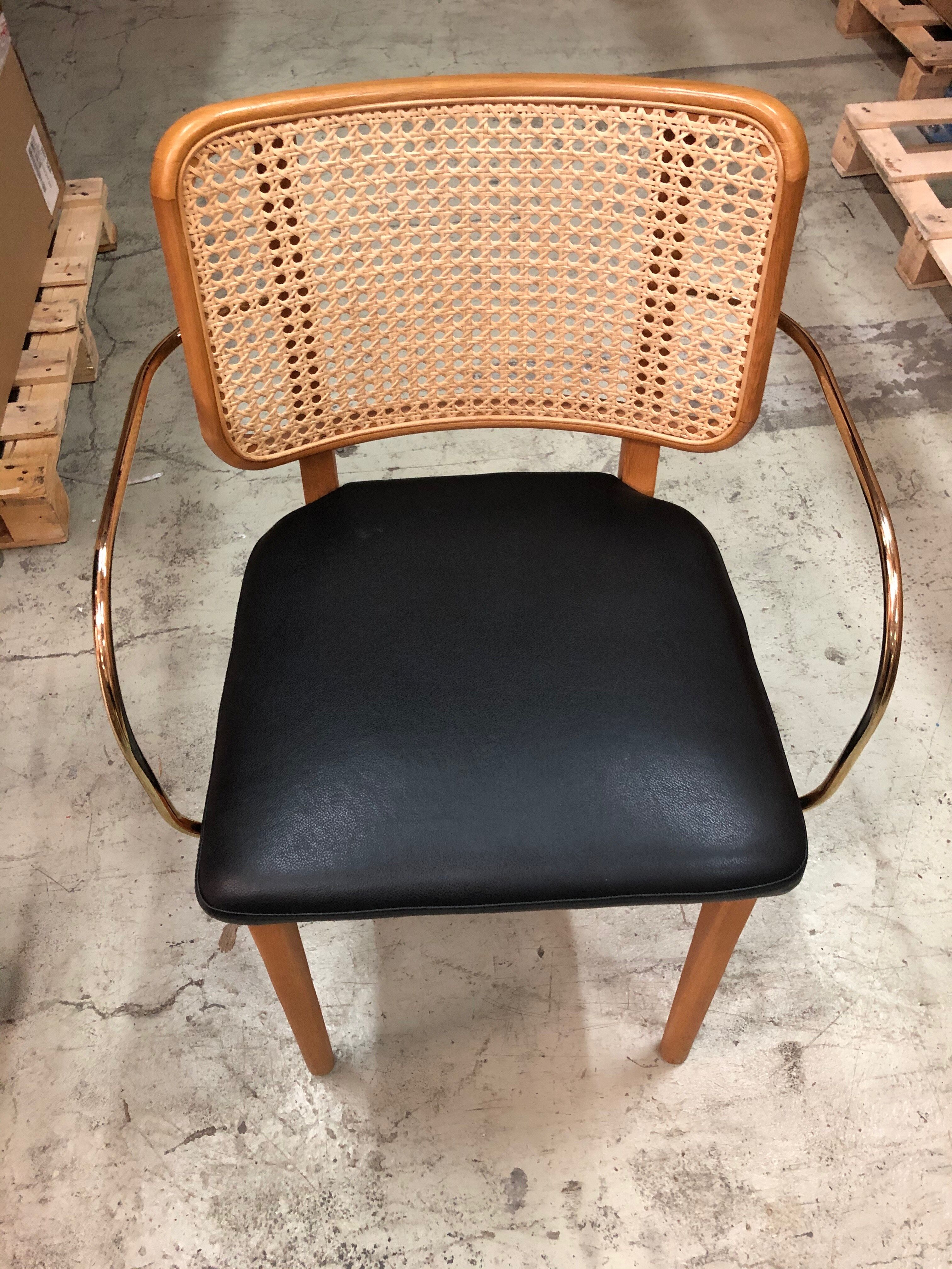 Light wood caning chair with black leather armrests