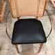 Light wood caning chair with black leather armrests