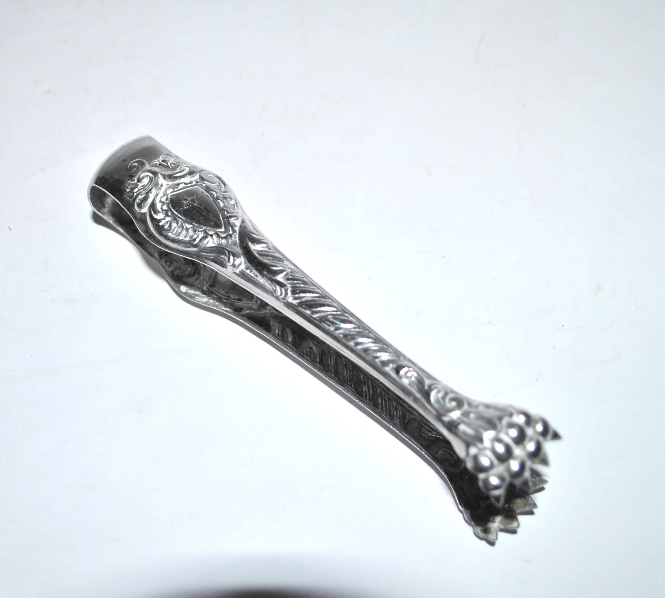 Rocaille sugar tongs in silver metal with lion claw medallion