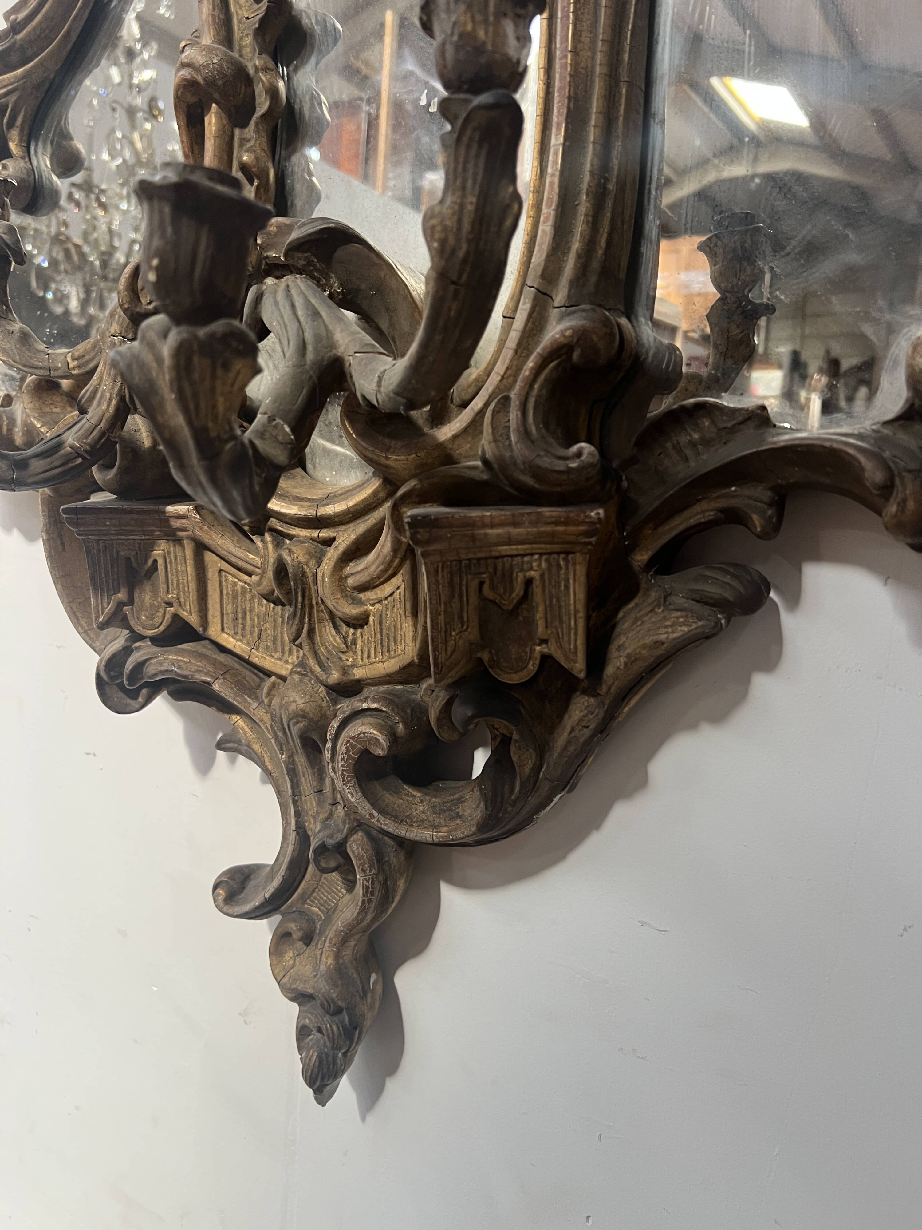 Mirror with a decorative frame featuring a four-light wall sconce, 19th century.