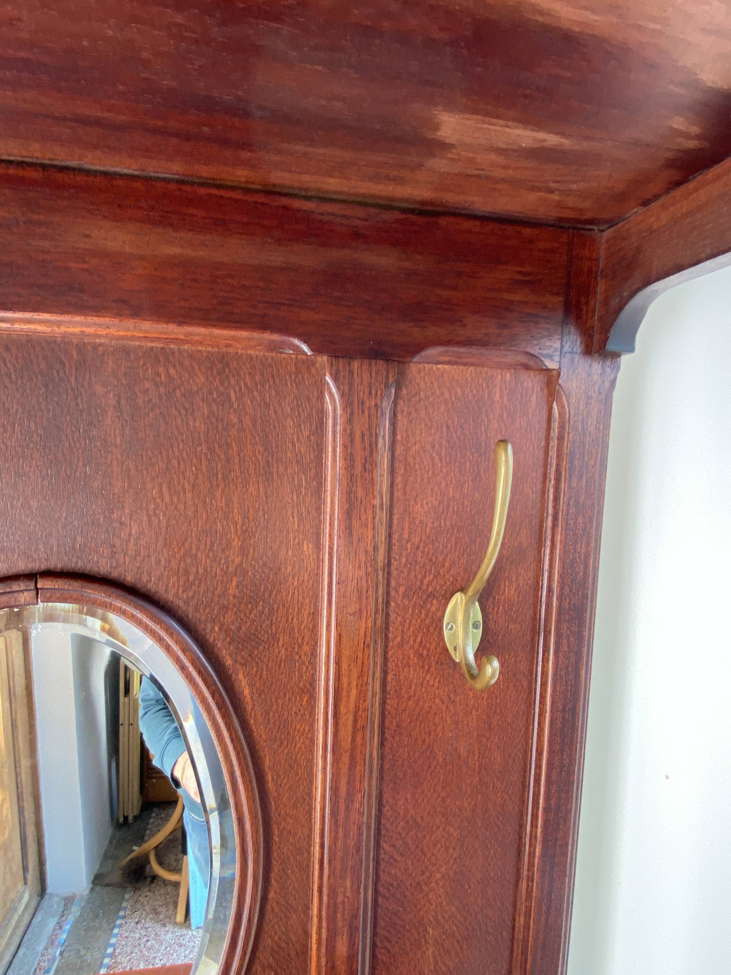 Antique wooden coat rack with mirror and shelf.