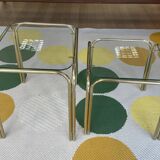 Pair of small nesting coffee tables in gold tubular metal & transparent glass tops