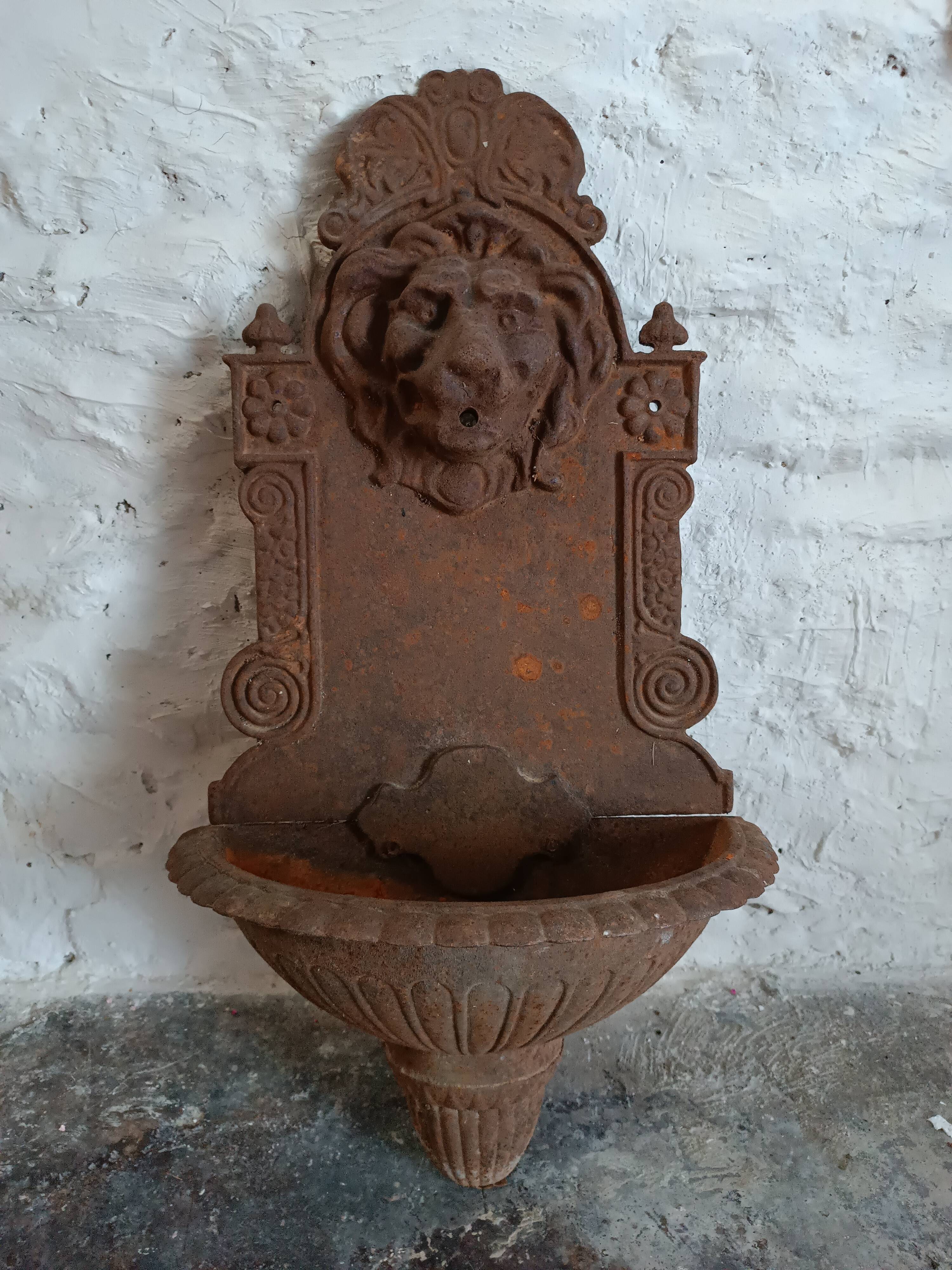 Old cast iron wall fountain with lion's head