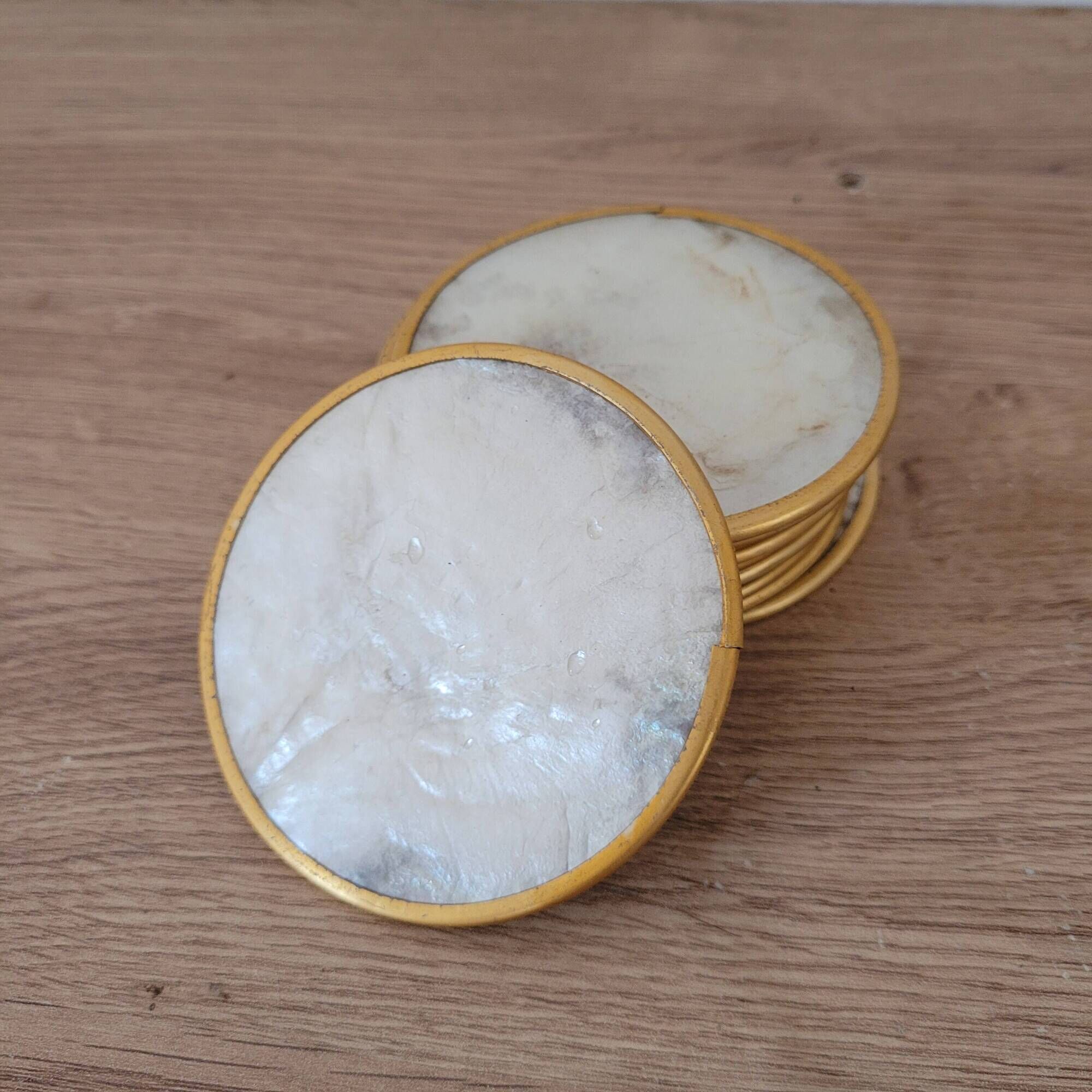 Set of 11 mother-of-pearl coasters with brass rim.