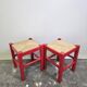 Tabouret en bois rouge avec assise en paille tressée.