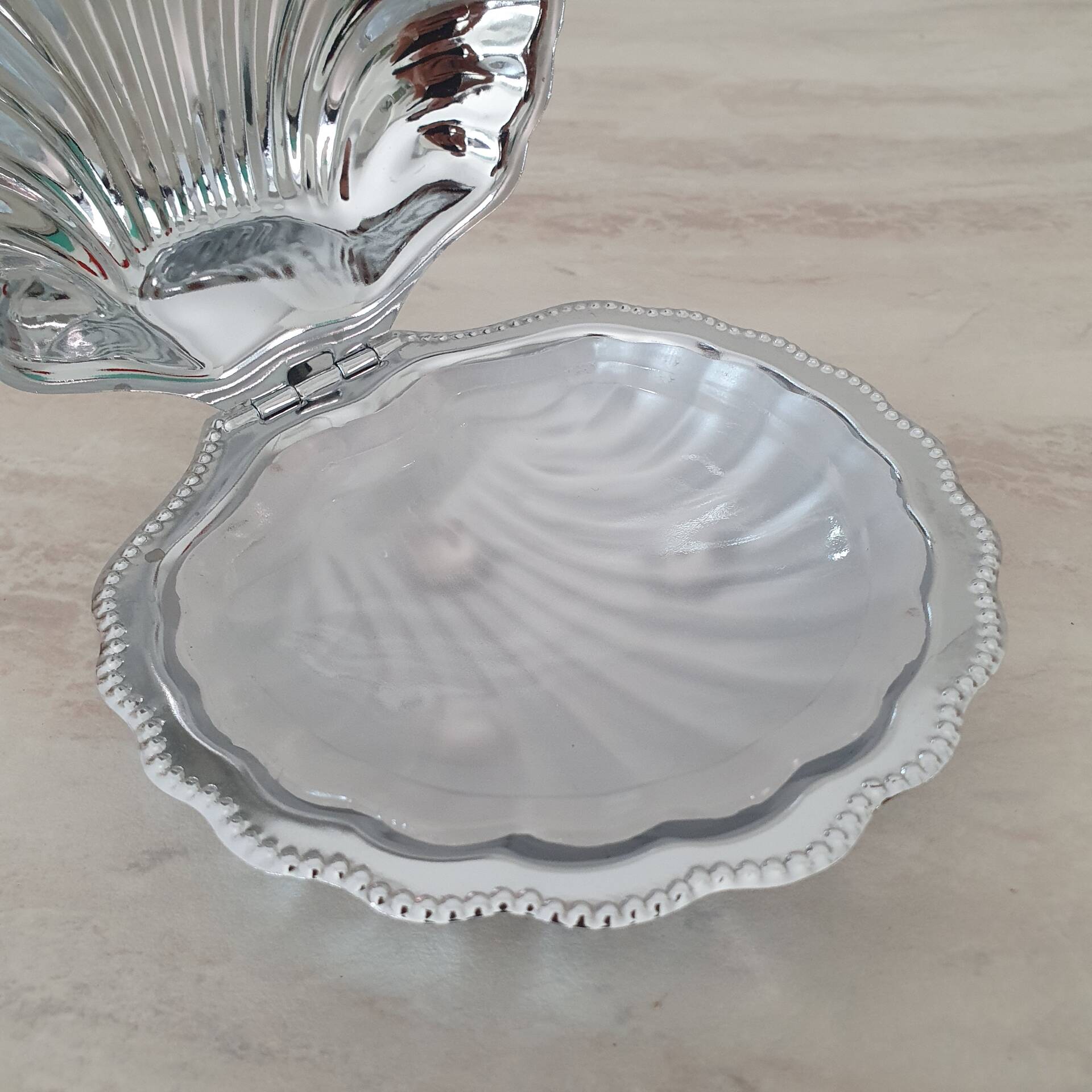 Shell-shaped butter dish in stainless steel and white glass bowl.