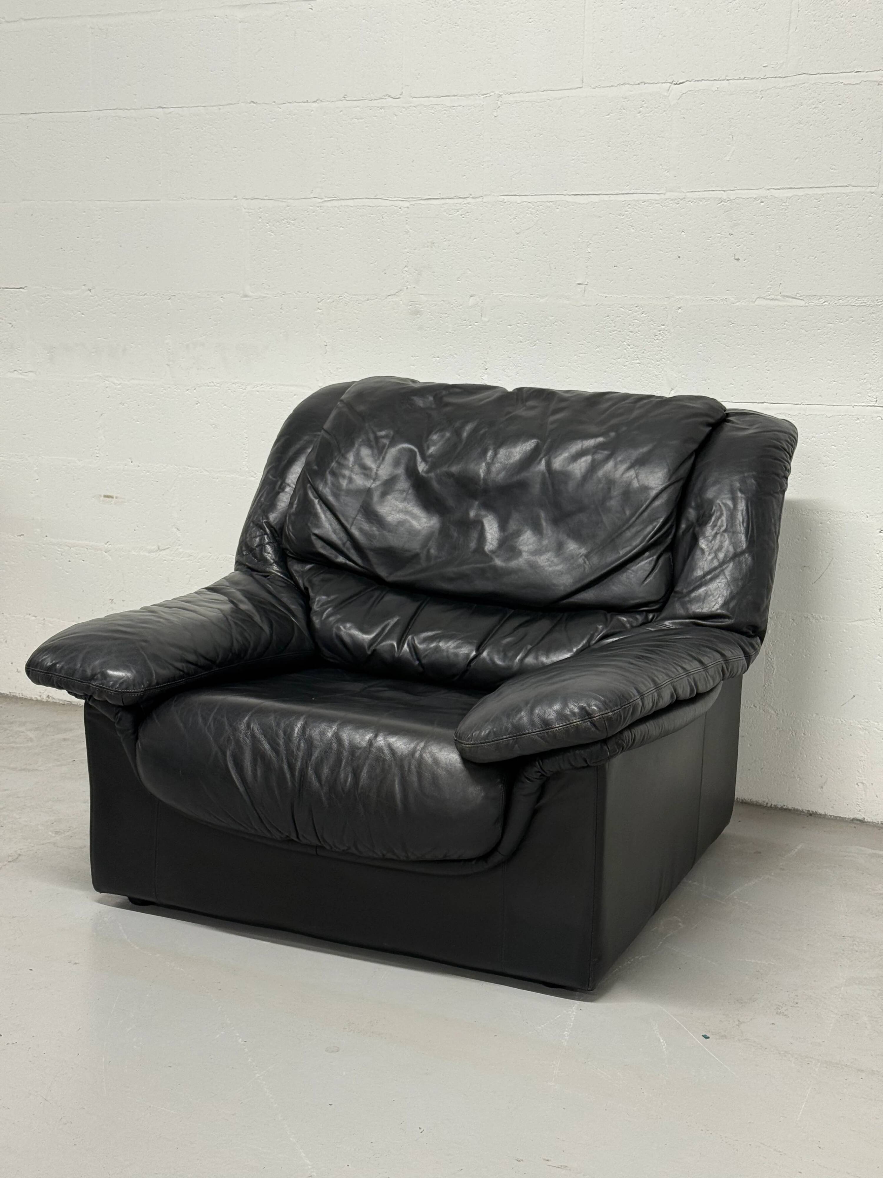 Vintage black leather lounge chair — low postmodern club chair from the space age.