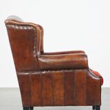 Sheep leather wingback chair with a red corduroy seat cushion and patina