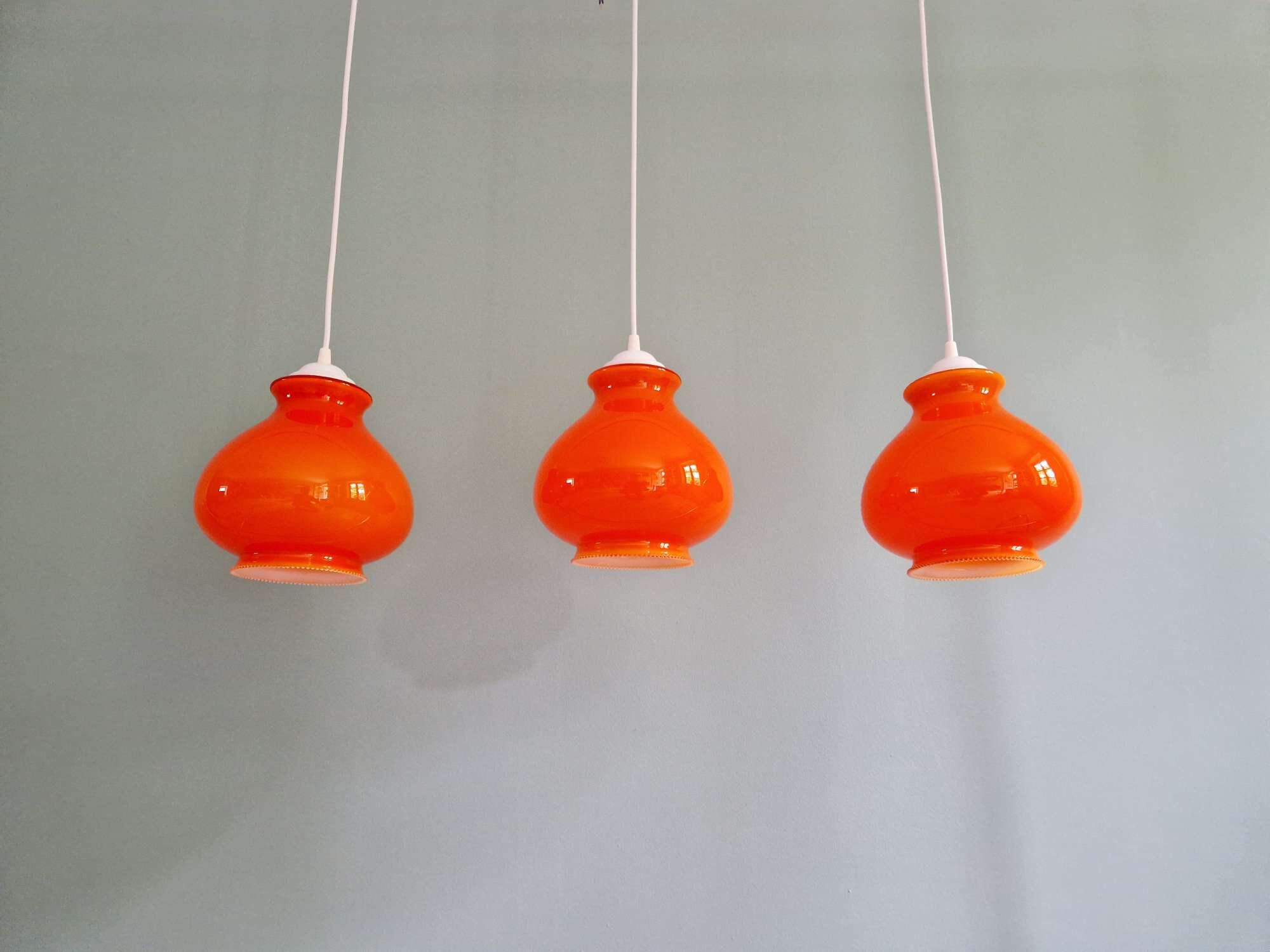 Trio of vintage orange opaline pendant lights, 1960-70