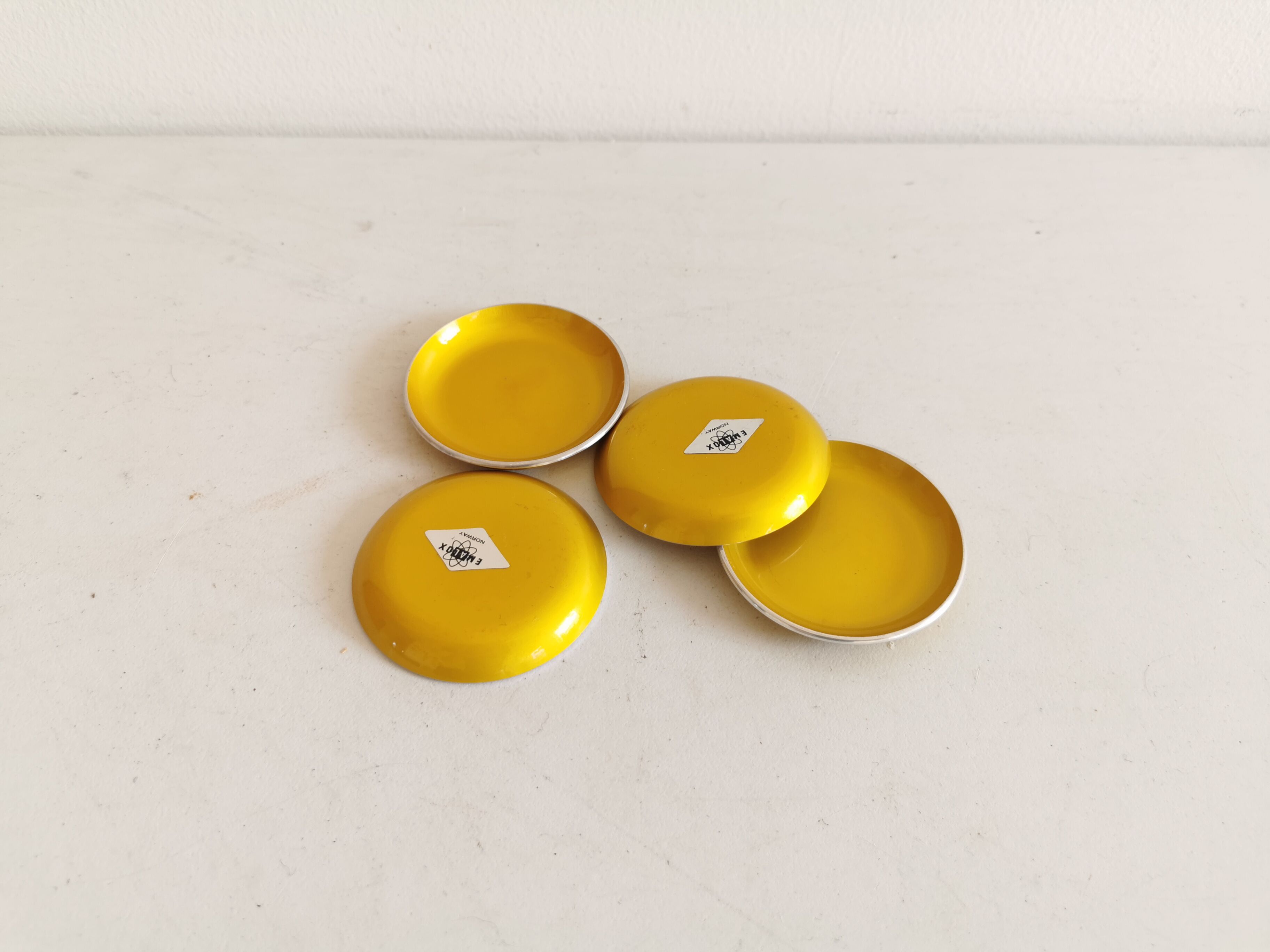 Ensemble de quatre sous-verres émaillés - cendriers de couleur jaune d’origine.