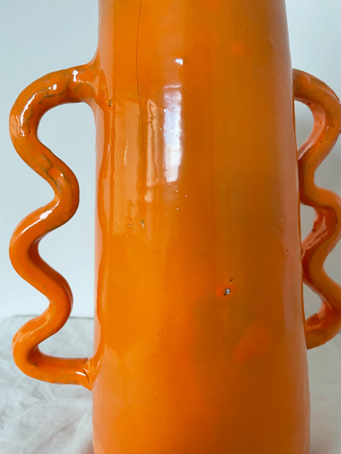 Handmade abstract orange ceramic vase with wavy handles
