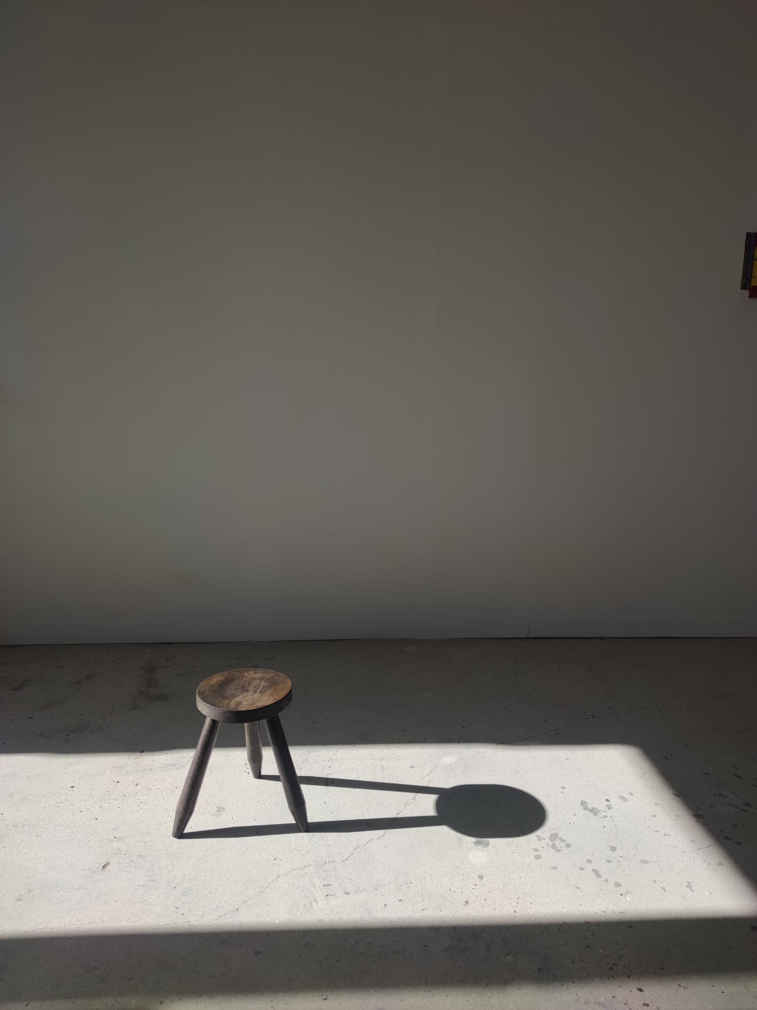 Small brutalistic tripod stool in dark wood tapered feet circular seat