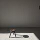 Small brutalistic tripod stool in dark wood tapered feet circular seat