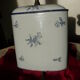Old wall fountain in enamelled sheet metal decorated with blue flowers on a white background