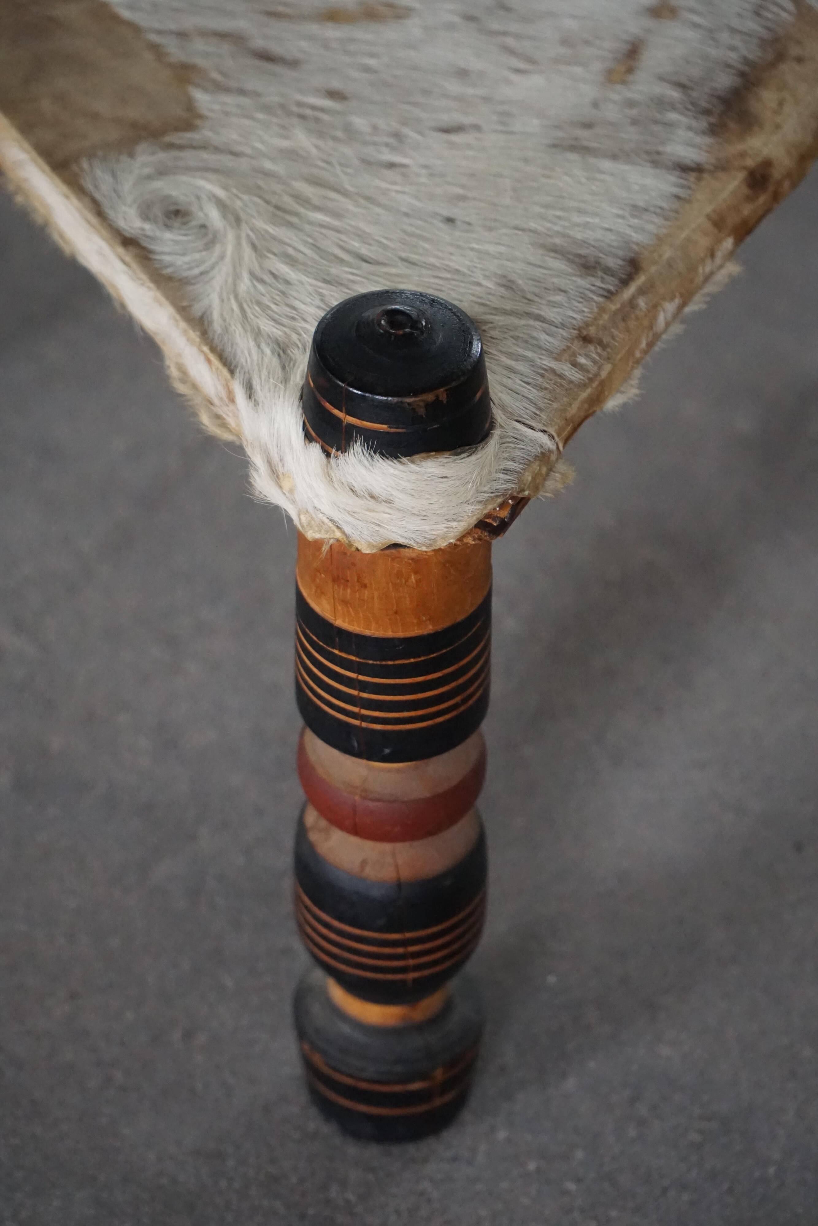Vintage African artisanal stool, triangular shape with 3 legs, cowhide, 20th century.