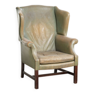 Fauteuil à oreilles en cuir de vache ancien de style anglais avec une belle patine.