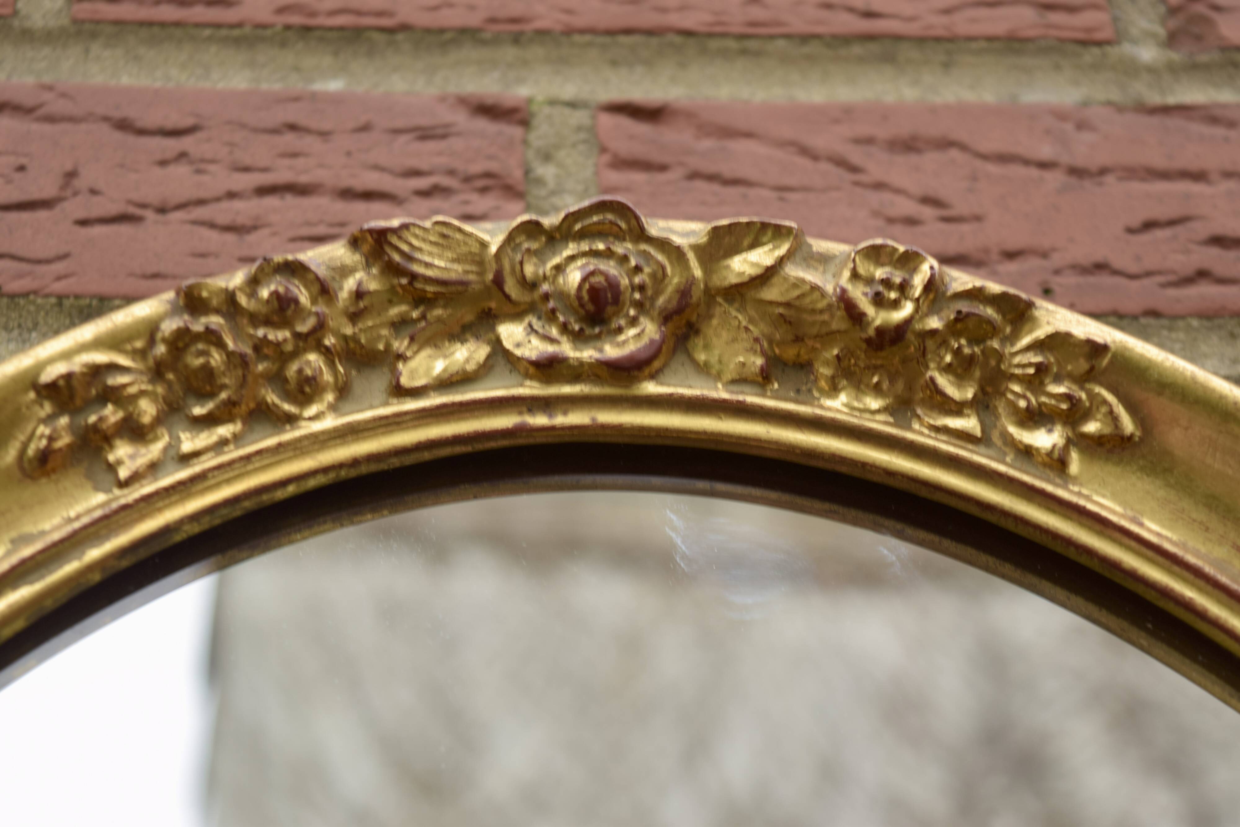 Old large oval wall mirror in golden resin