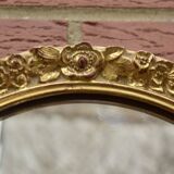 Old large oval wall mirror in golden resin