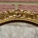 Old large oval wall mirror in golden resin