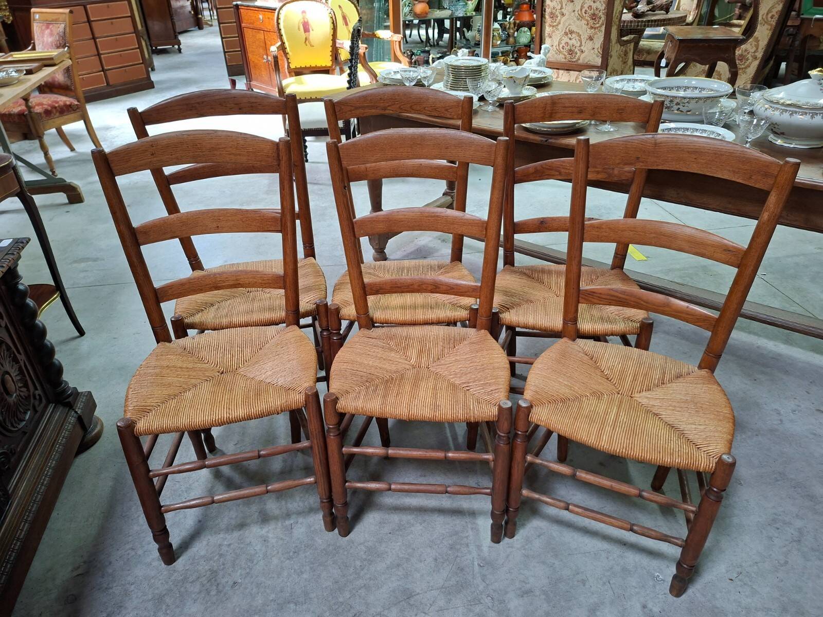Set of six rustic chairs in natural wood with straw seats.