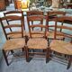 Set of six rustic chairs in natural wood with straw seats.