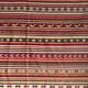 Large Indian rug with red, yellow, and white stripes and geometric fringes.