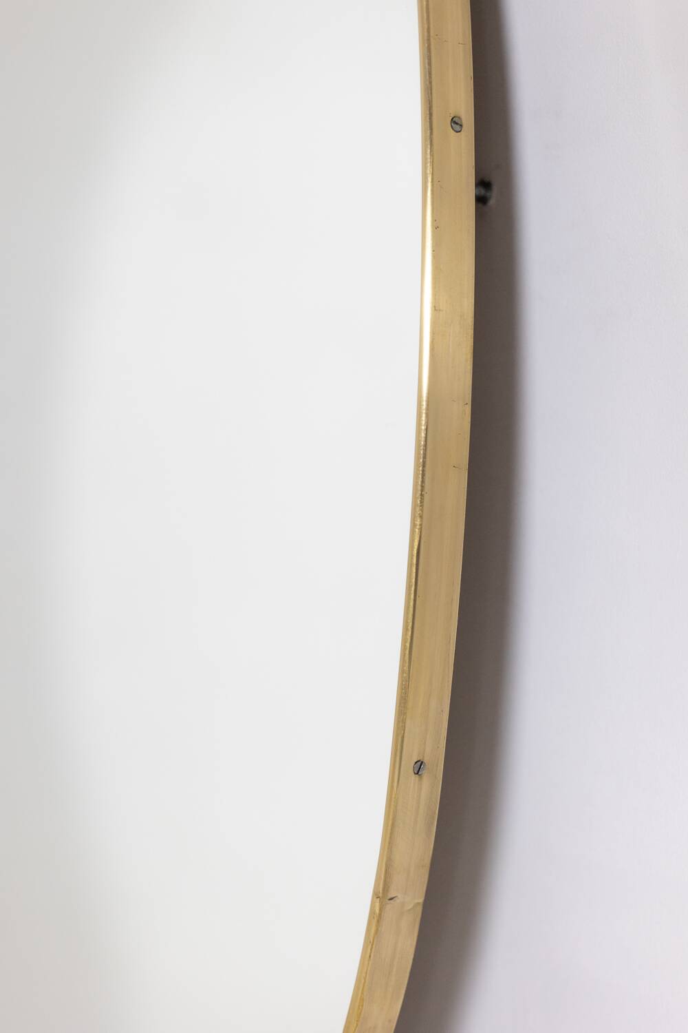 Oval shaped mirror set with a gilded brass rod. 1970s.