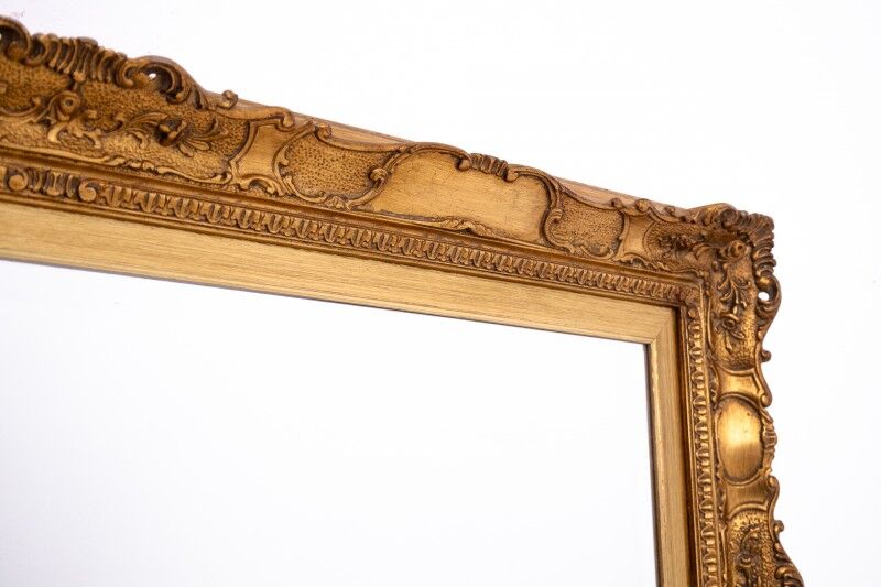 A mirror with a golden, richly carved frame.