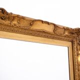 A mirror with a golden, richly carved frame.