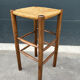 Old high bar stool in wood and straw