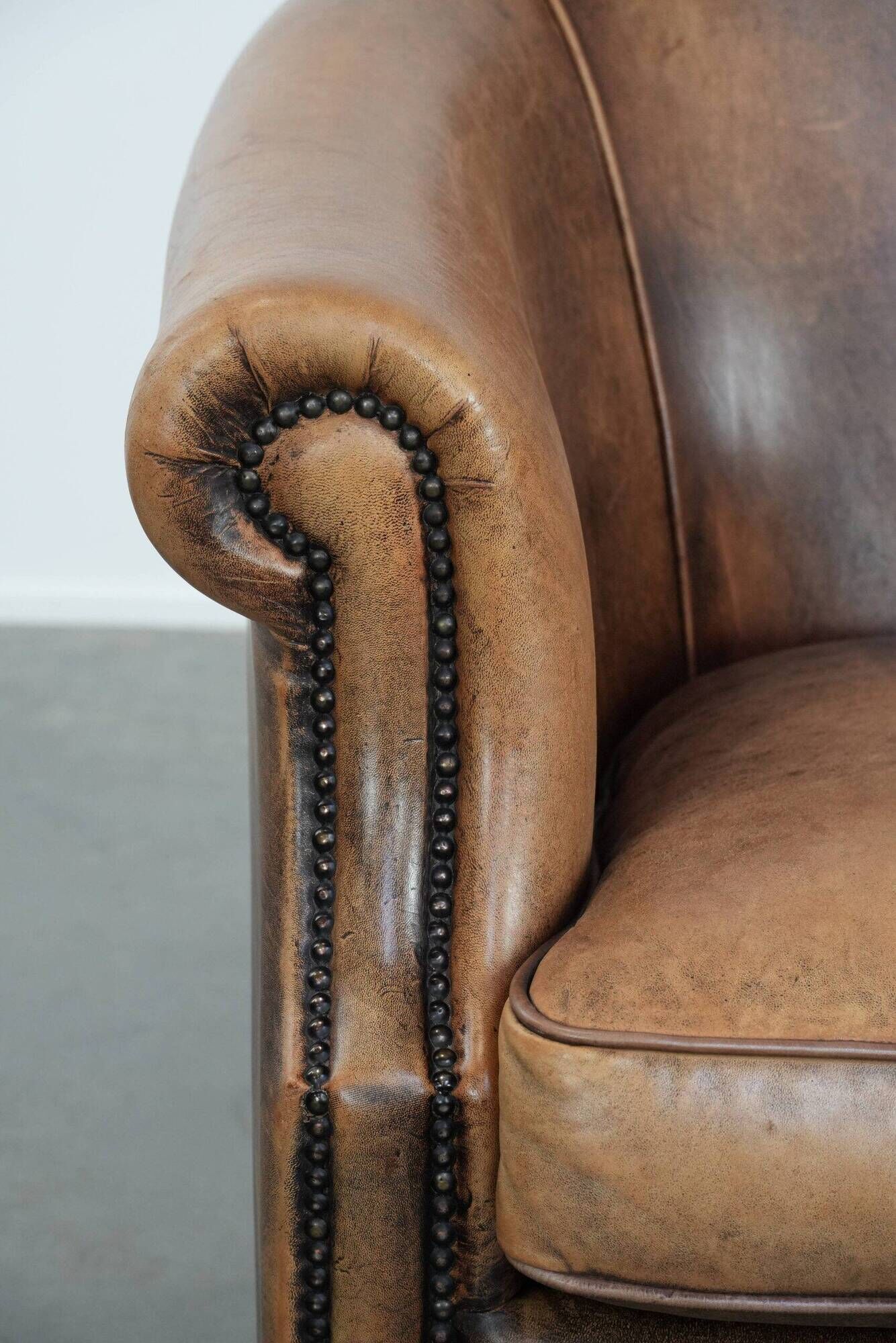 Club chair made of sheepskin leather finished with decorative nails