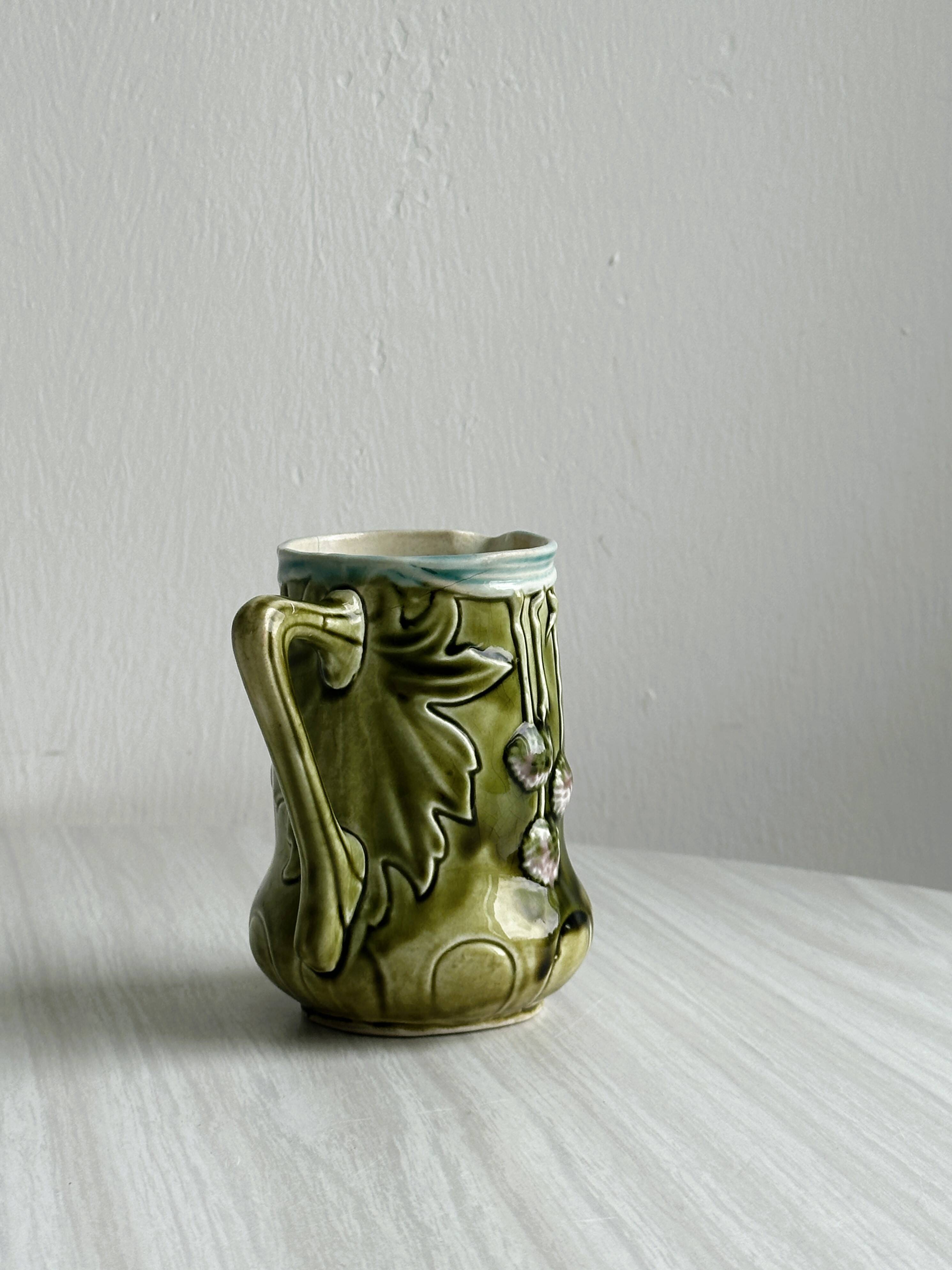 Green slip milk jug with floral patterns.