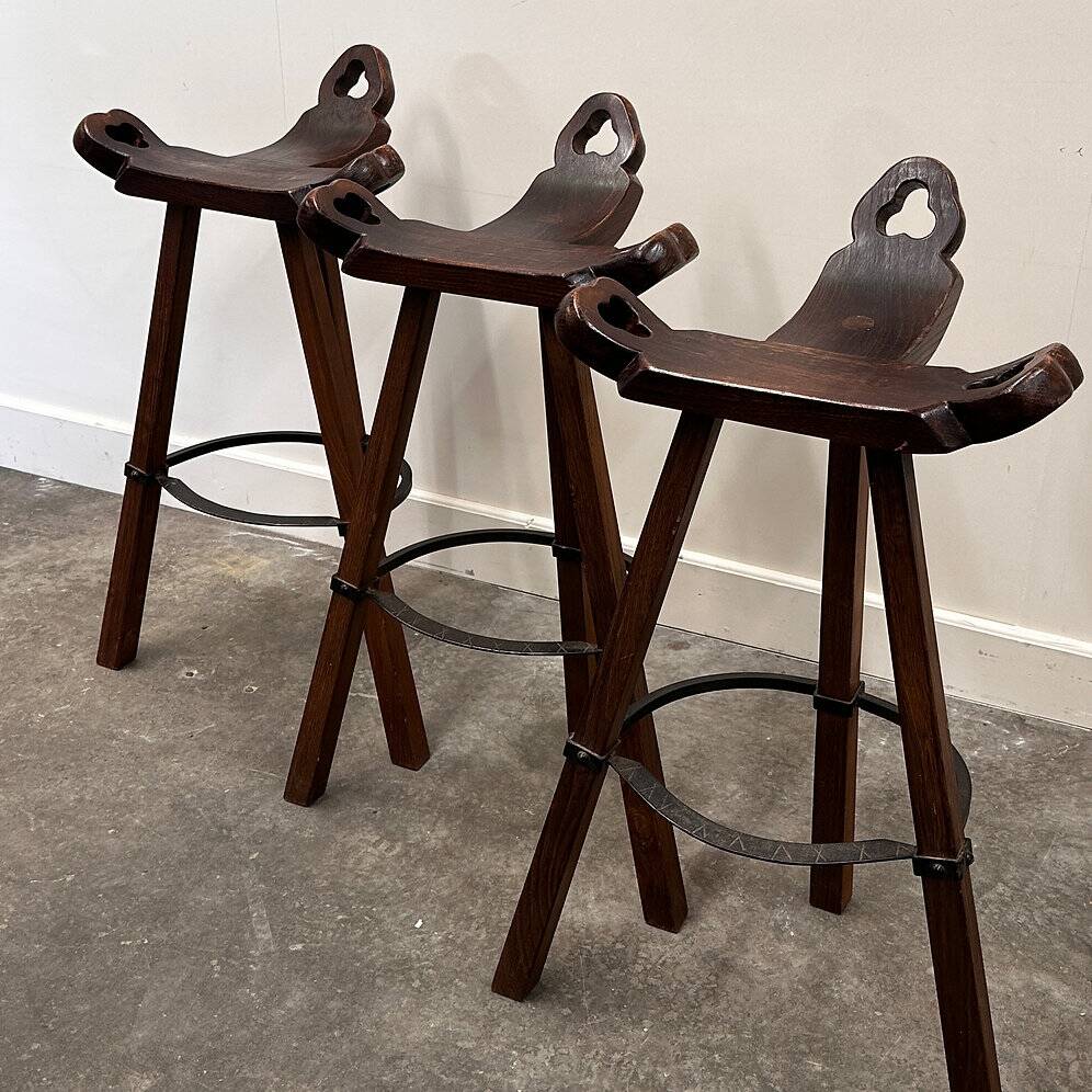Set of 3 rustic carved oak bar stools with iron footrests, 1970s