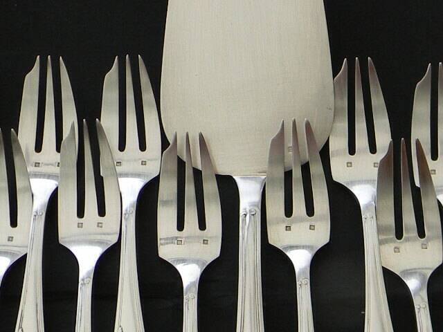 12 cake forks and a silver metal server.