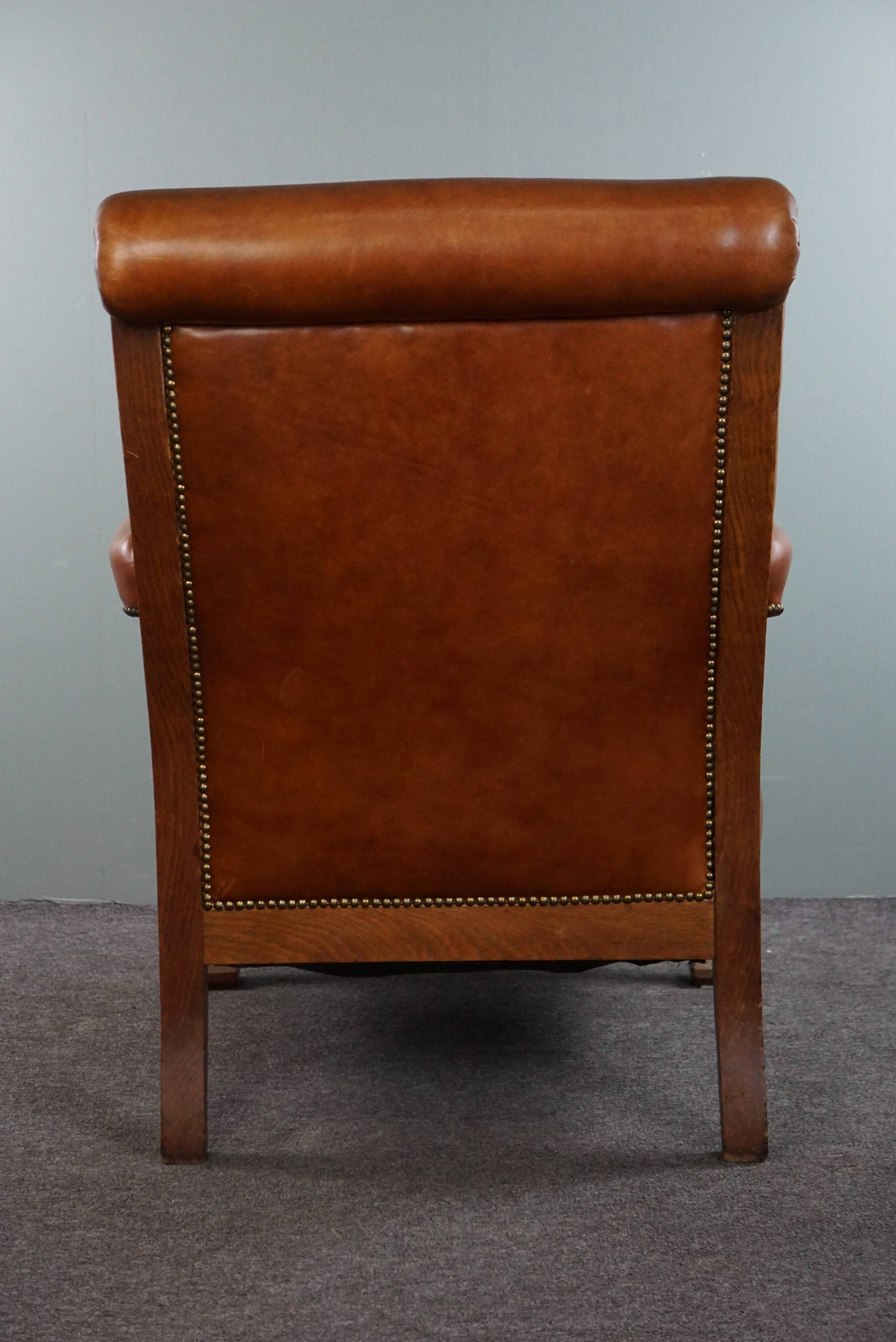 Armchair with lion heads reupholstered in cognac-colored cowhide leather