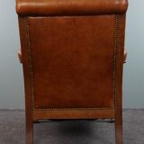 Armchair with lion heads reupholstered in cognac-colored cowhide