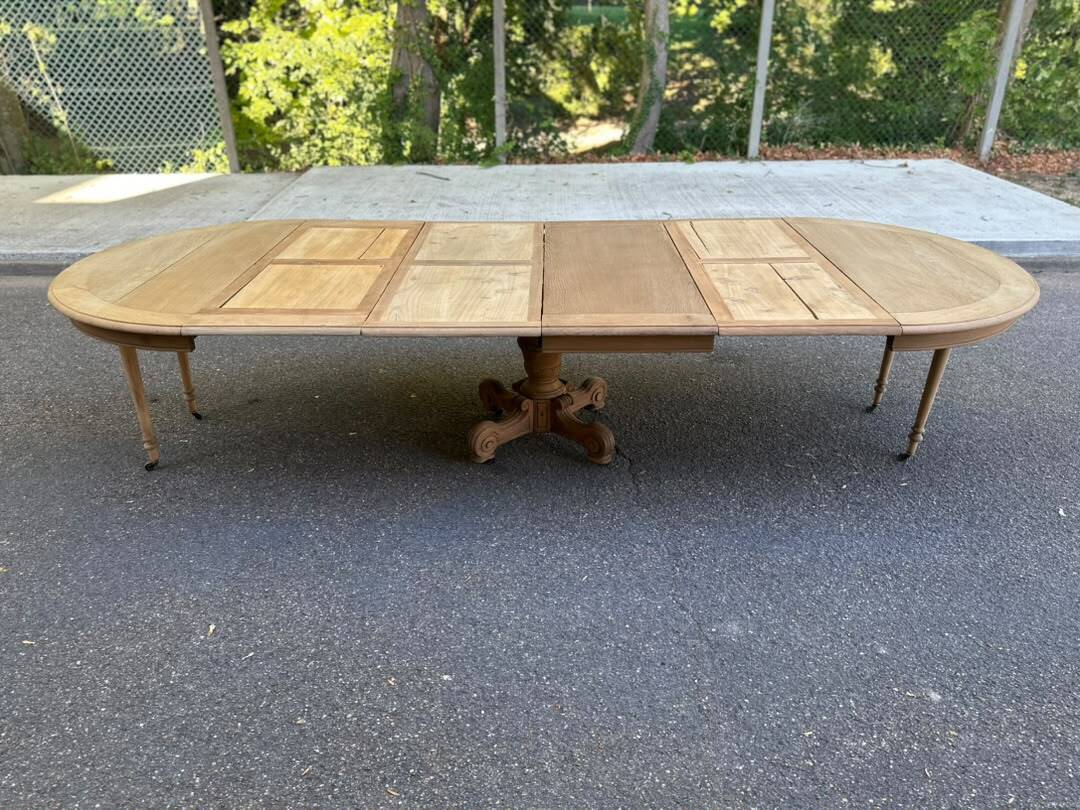Round dining table with a central pedestal, stripped raw oak, 4 extensions, 19th century.