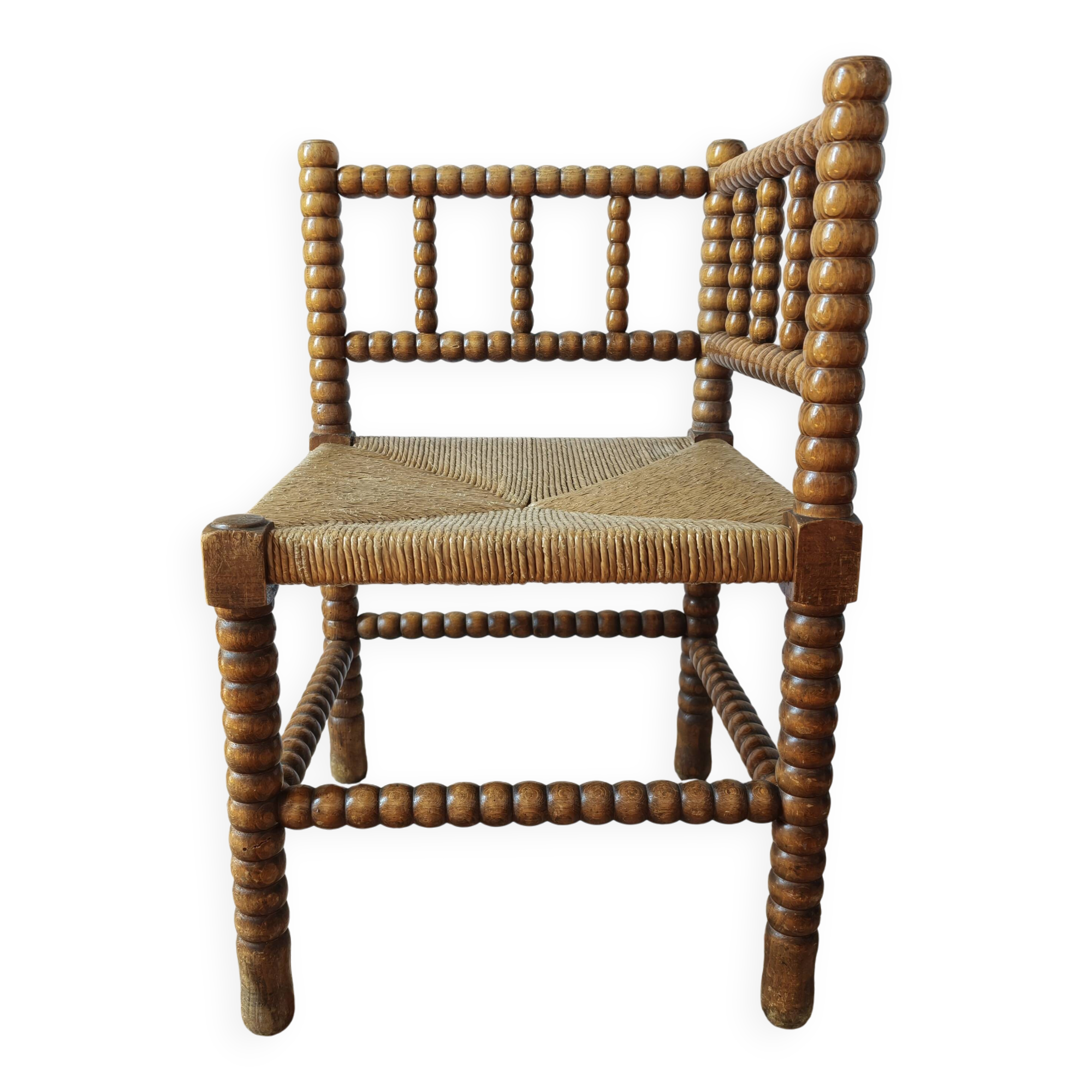 Antique corner chair by the fire with turned wood and straw seat.
