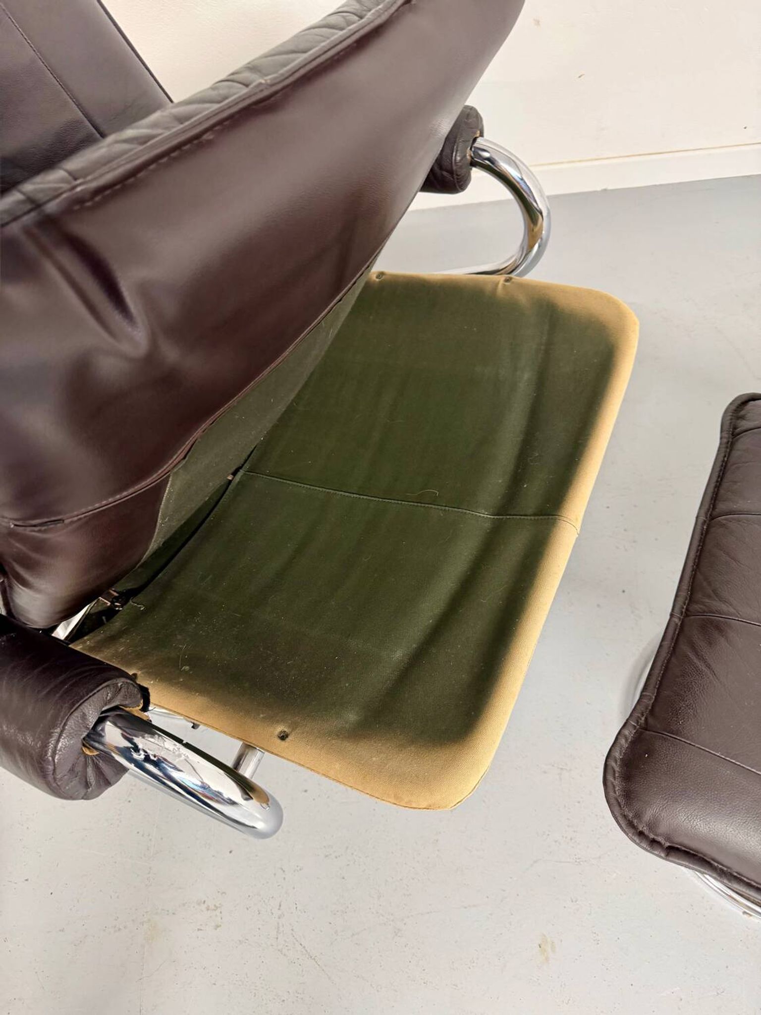 Vintage leather reclining armchair and its 1970s designer ottoman.