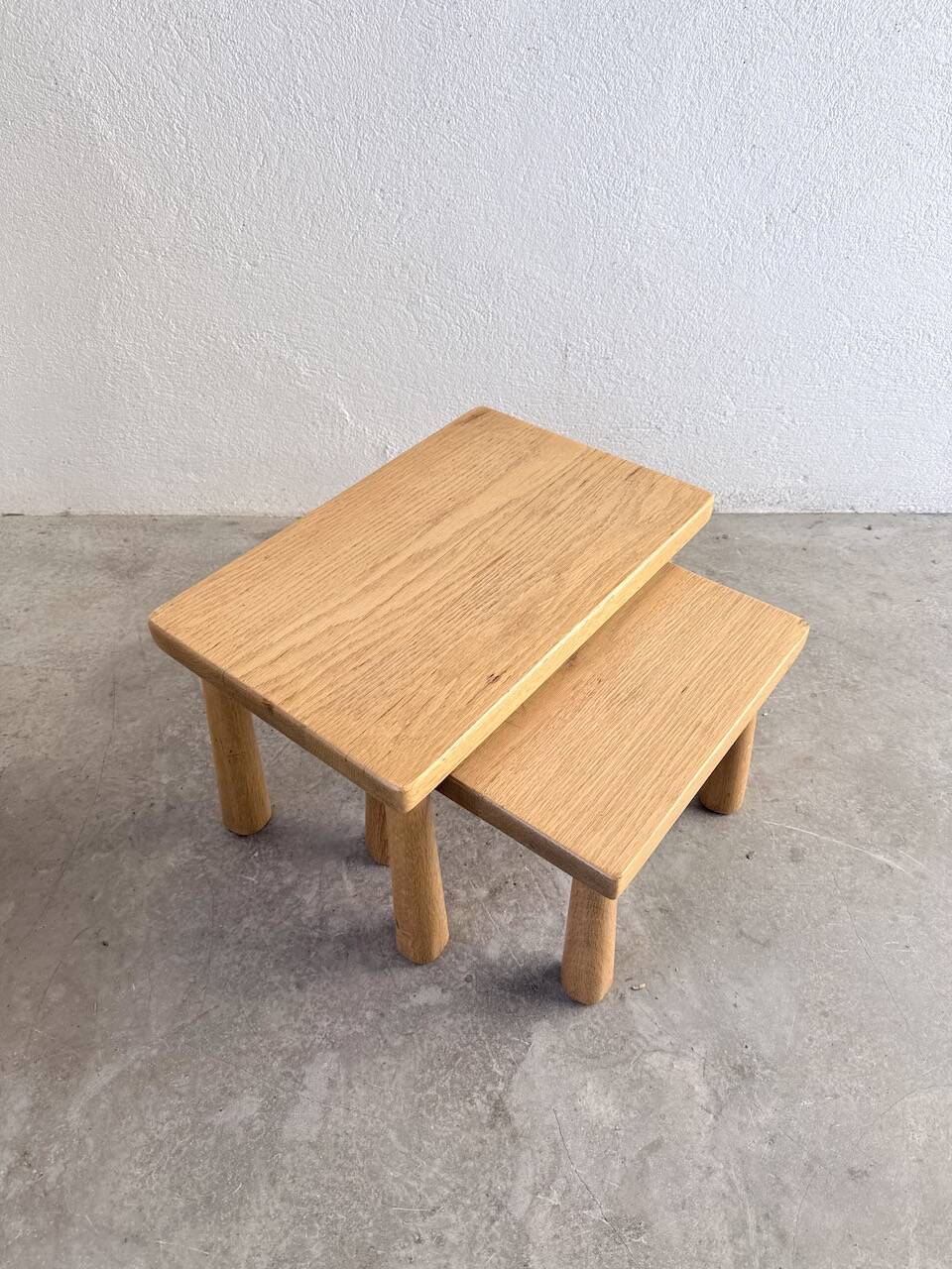 Two stools or small nesting tables in light oak.