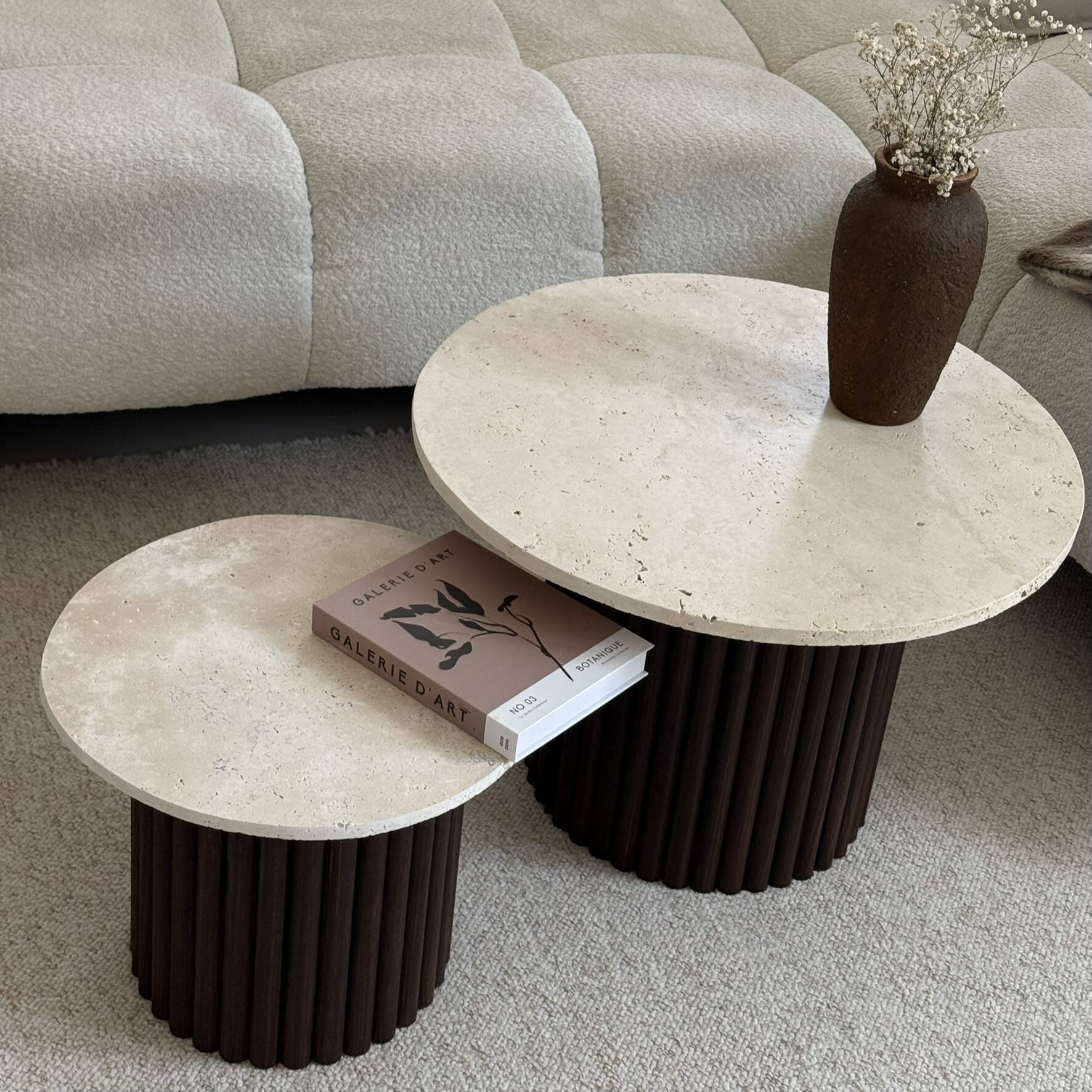 Round nesting coffee table in travertine and dark fluted wood.