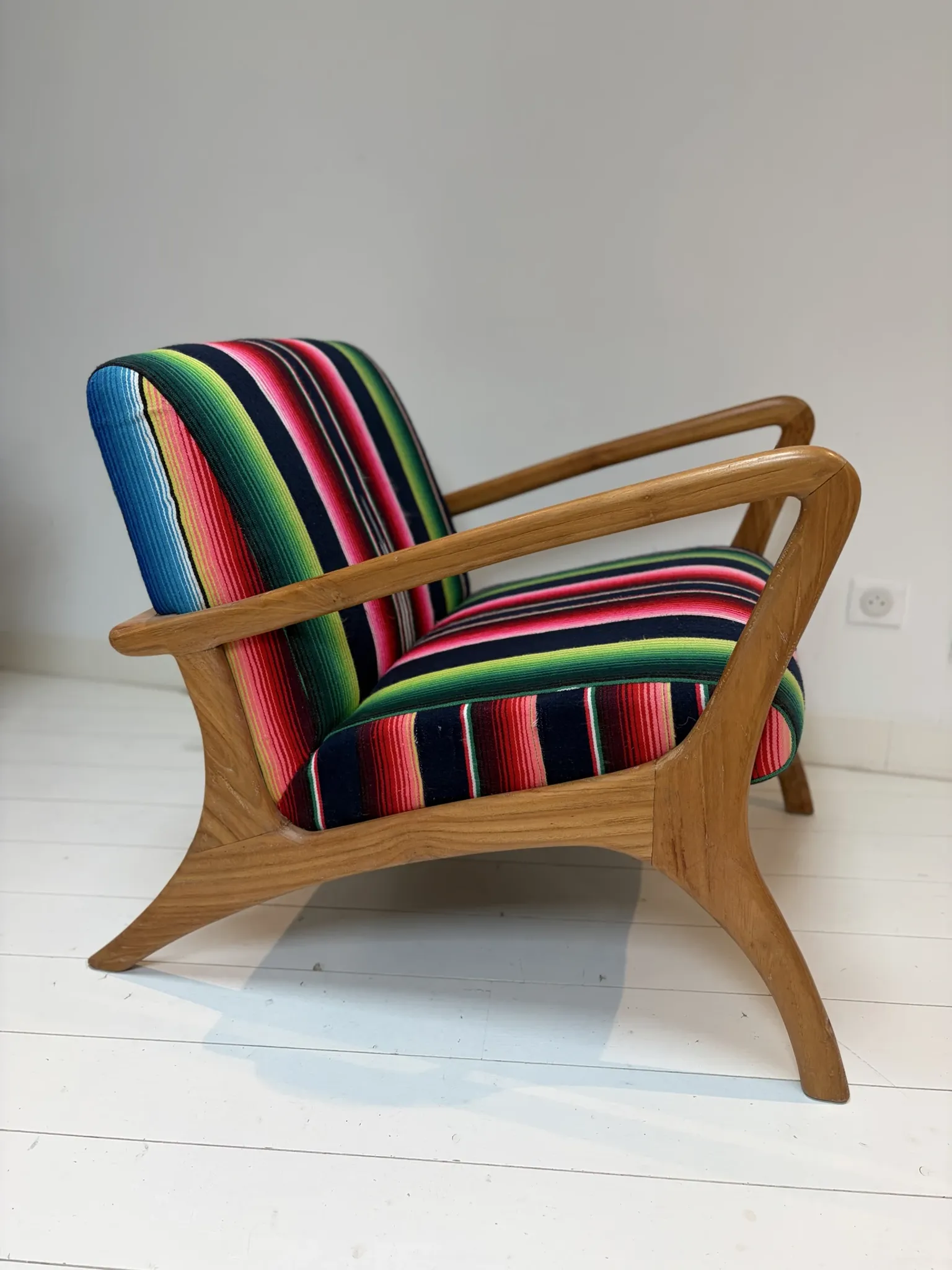 Scandinavian-style armchair in curved wood and colourful striped fabric.
